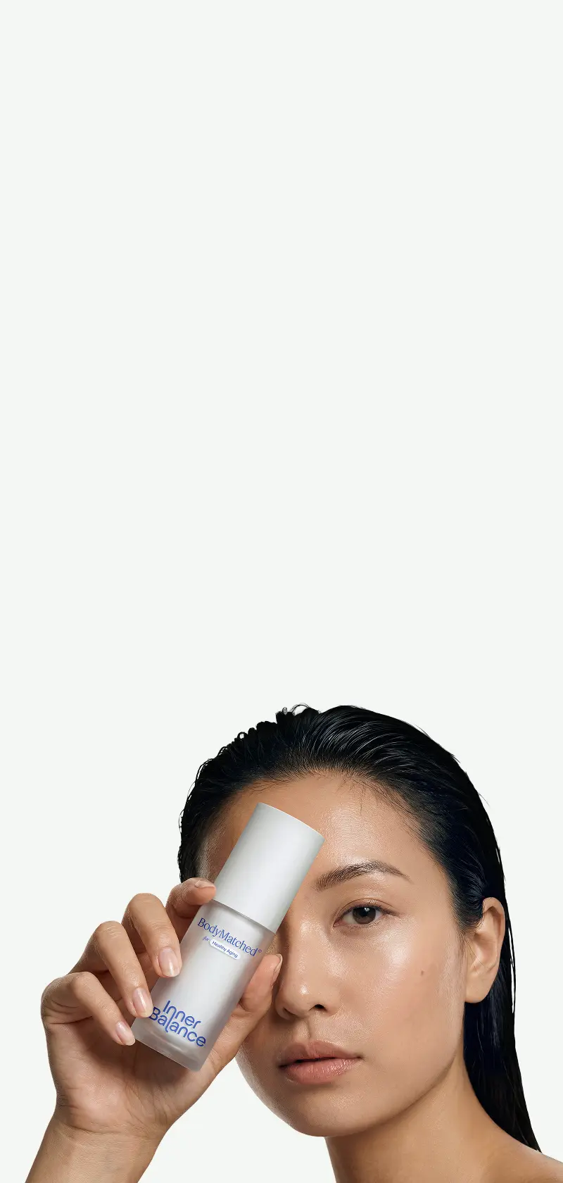 Woman holding BodyMatched® niacinamide face cream to her face